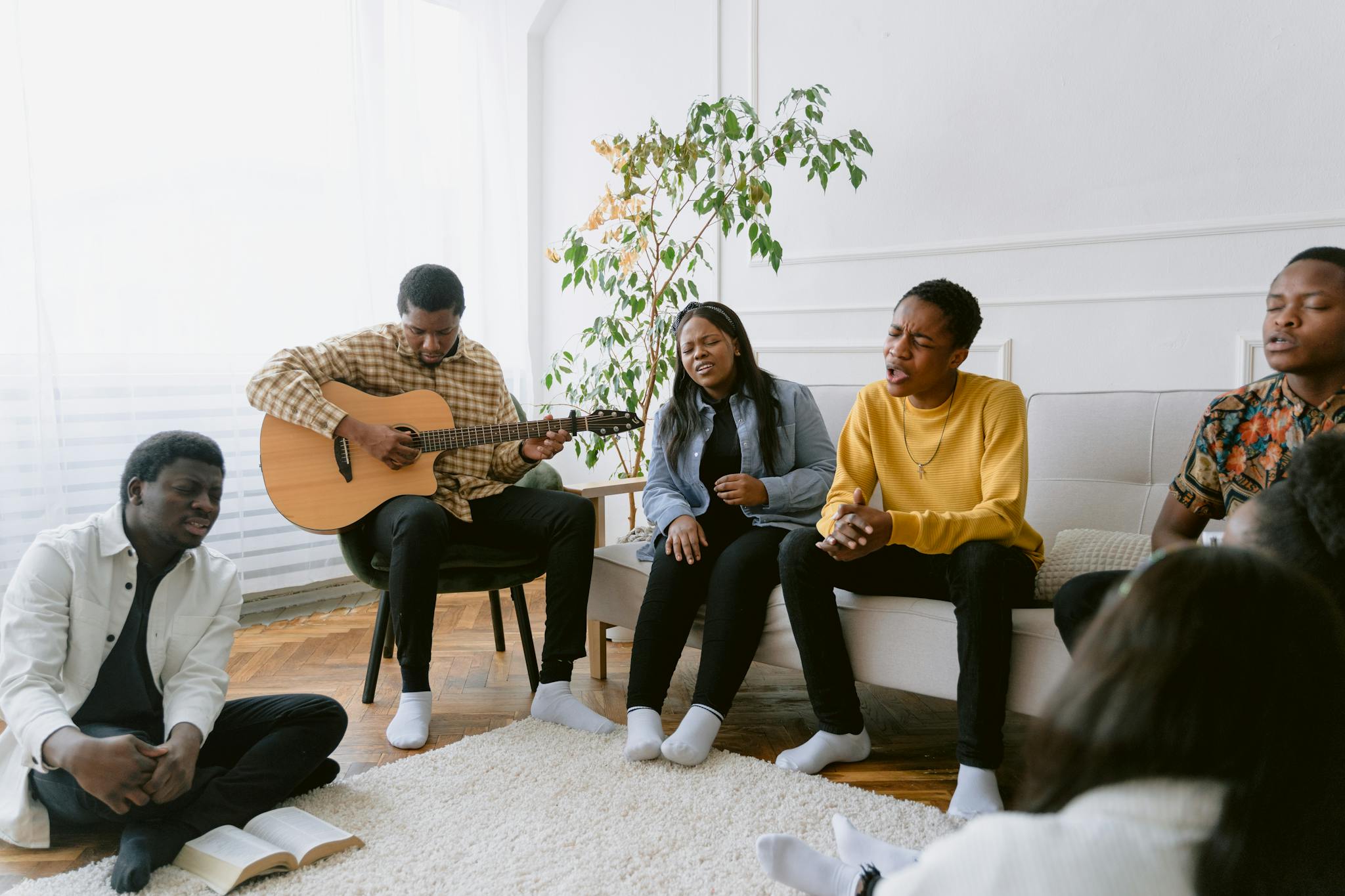 A group of friends singing and playing guitar together in a cozy indoor setting.